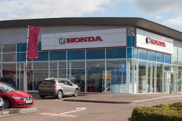 Exterior view of a Honda dealership with parked cars in front.